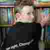 A child sorting out books in a bookshelf. His t shirt says save sight. change lives. 