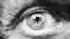 Extreme close up of an eye in black and white. The lines around the eye imply it belongs to someone of an older age. 