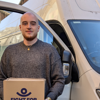 Fight for Sight house clearances, a smiling man stood by a white van holding a box with the navy Fight for Sight logo on it.