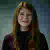 Rebecca is a young white woman with long red hair. She is smiling for the camera.