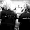 Black and white image of the back of two people cheering at the London Marathon. On the back of their shirts are the words 'Save Sight. Change Lives.'