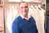 A photo of Phil Beavan from the waist up standing in front of a shop display.