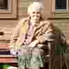 Older photo of woman on a bench wearing sunglasses